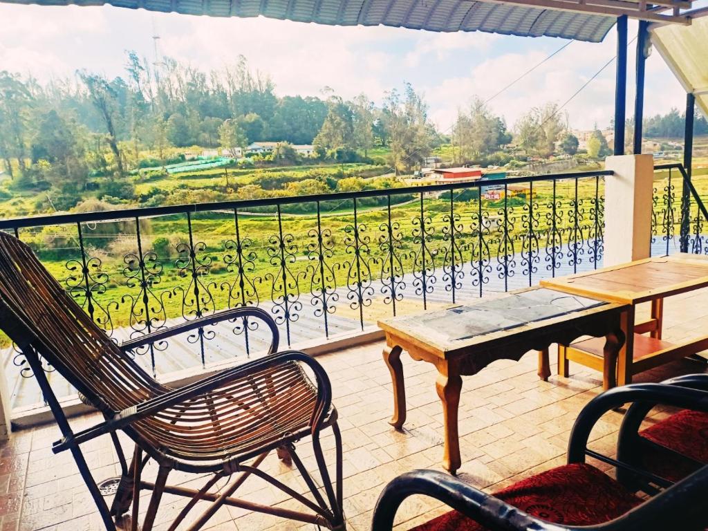 a balcony with a table and chairs and a view at SNR Cottage & Rooms in Ooty