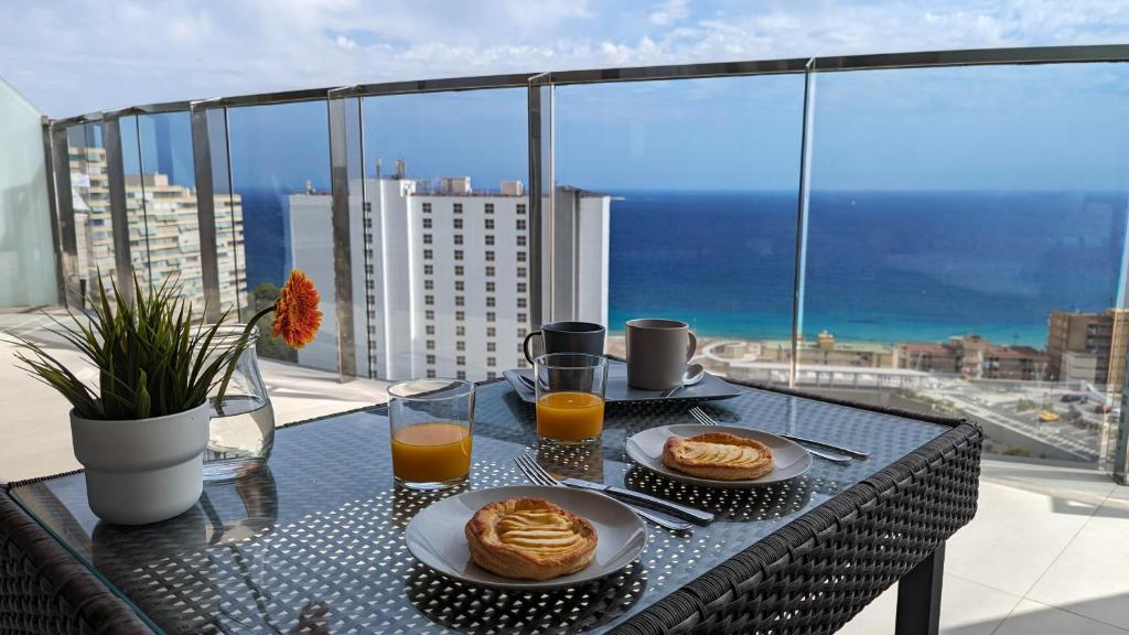 una mesa con dos platos de comida y dos vasos de zumo de naranja en SUNSET WAVES sea view apartments, en Benidorm