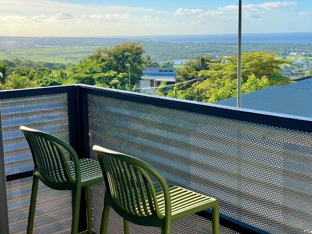 - deux chaises vertes assises sur un balcon avec vue dans l'établissement Aloes - Villa Salba. Panoramic view., à L'Étang-Salé