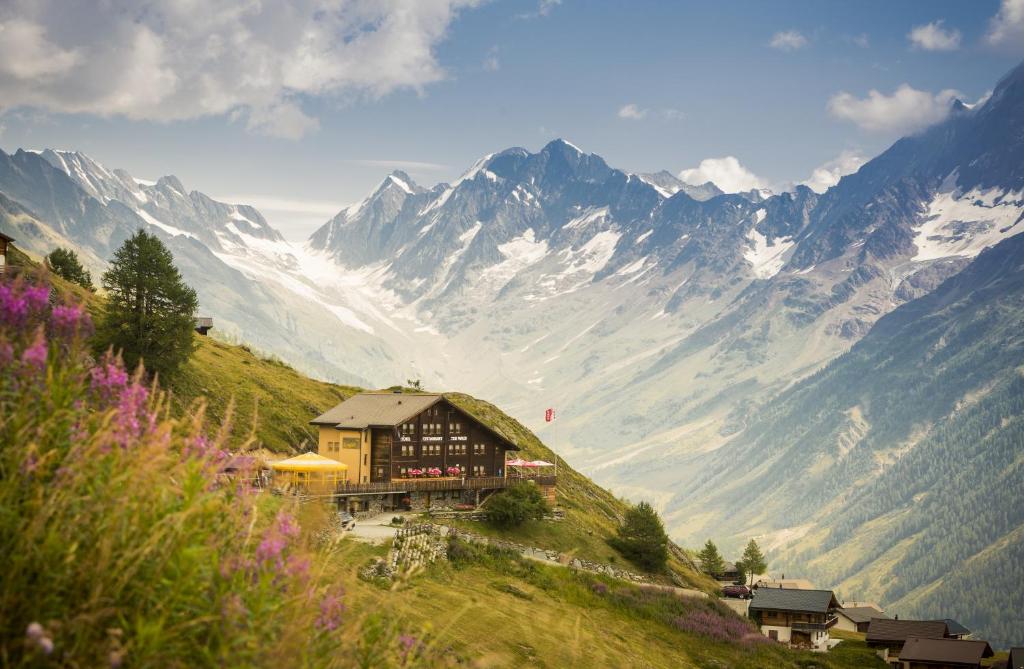 a building on a hill with mountains in the background at Alpenhotel zur Wildi in Wiler