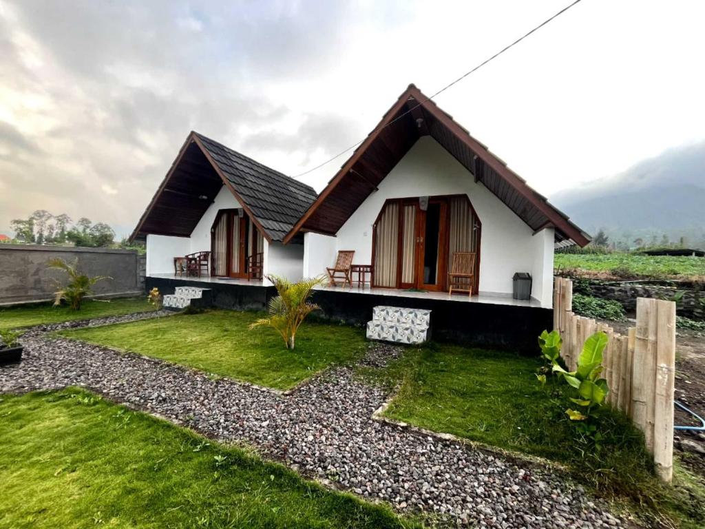 a small white house with a fence and grass at Serene Wilderness Villa Batur Natural Hot Spring in Kintamani