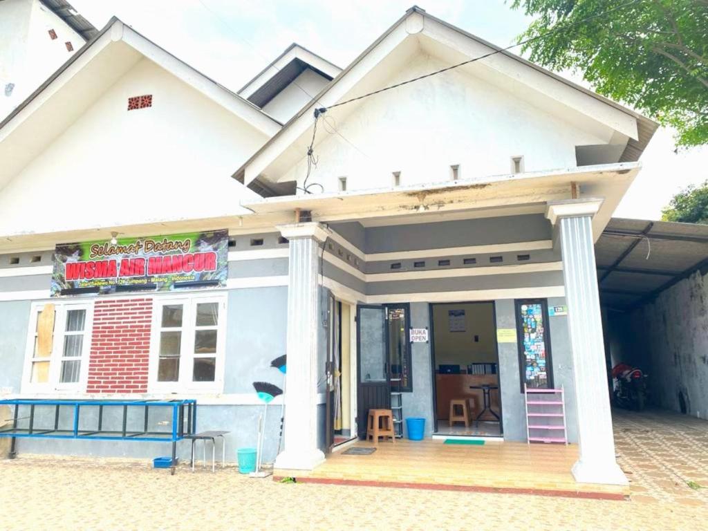 un magasin à l'avant d'une maison avec une terrasse couverte dans l'établissement OYO 93571 Wisma Air Mancur Homestay, à Malang