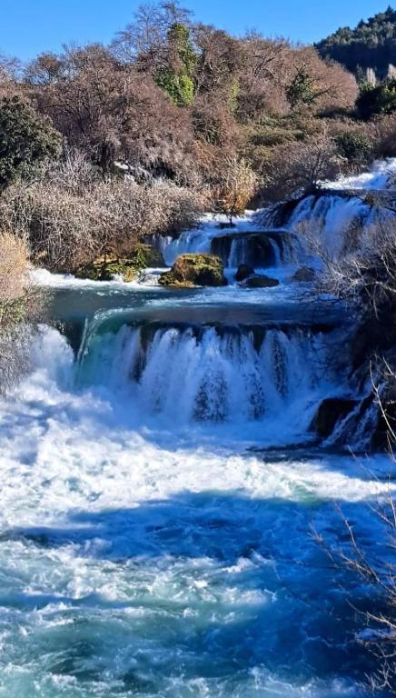 a river with blue water and trees in the background at Restaurant &amp; rooms Visovac - best value in Skradin