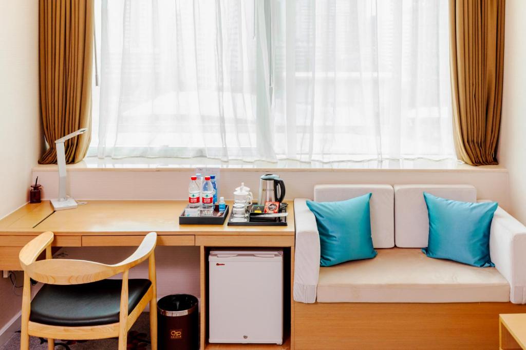 a room with a desk and a couch with blue pillows at China Mayors Plaza - Free shuttle between hotel and Exhibition Center during Canton Fair in Guangzhou