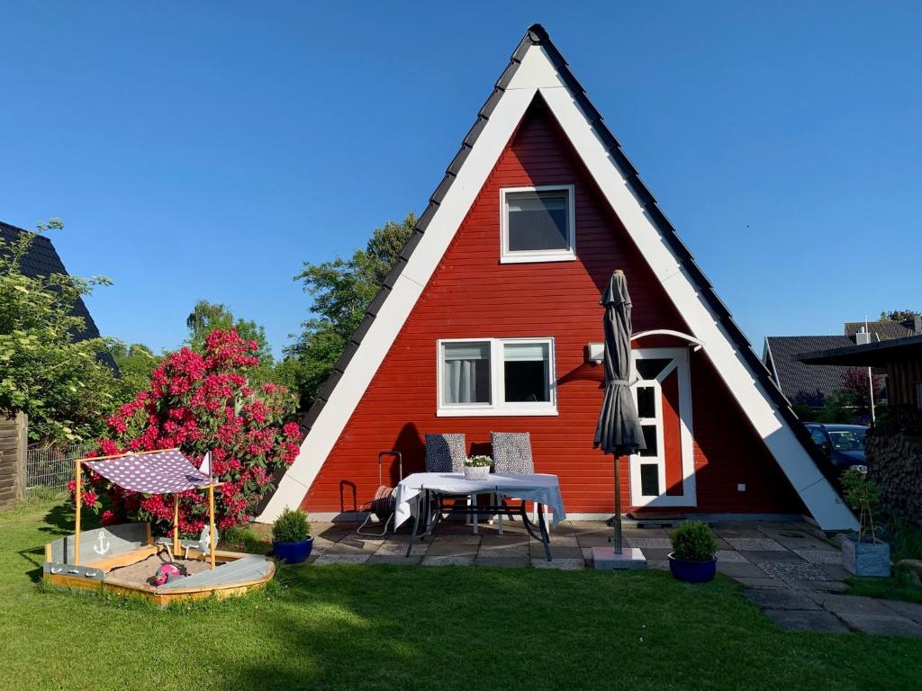 a house with a triangular roof with a table in the yard at Schleimöwe in Borgwedel