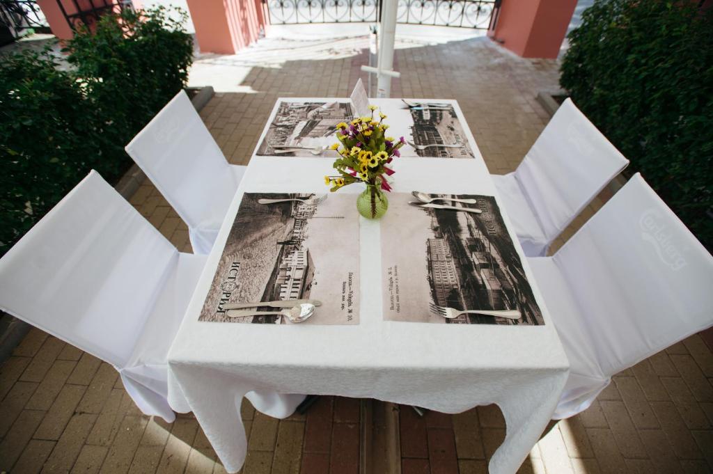 a white table with a vase of flowers on it at History Hotel in Vologda