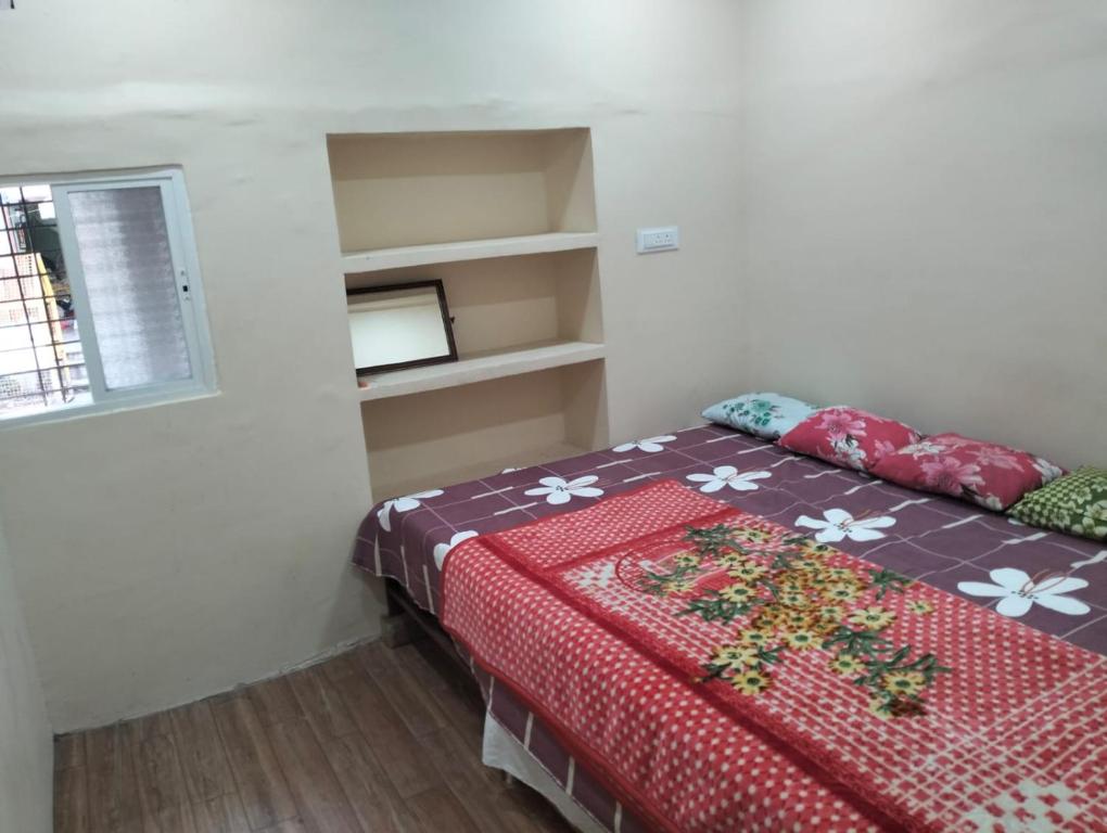 1 dormitorio con 1 cama con edredón rojo y ventana en MAA HARSIDDHI HOMESTAY, en Ujjain