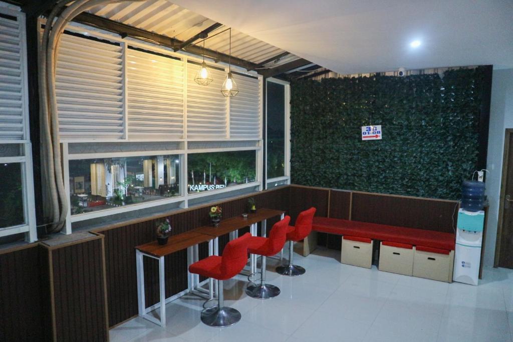 ein Restaurant mit roten Stühlen und eine Bar mit einem Fenster in der Unterkunft K1 UPN in Surabaya