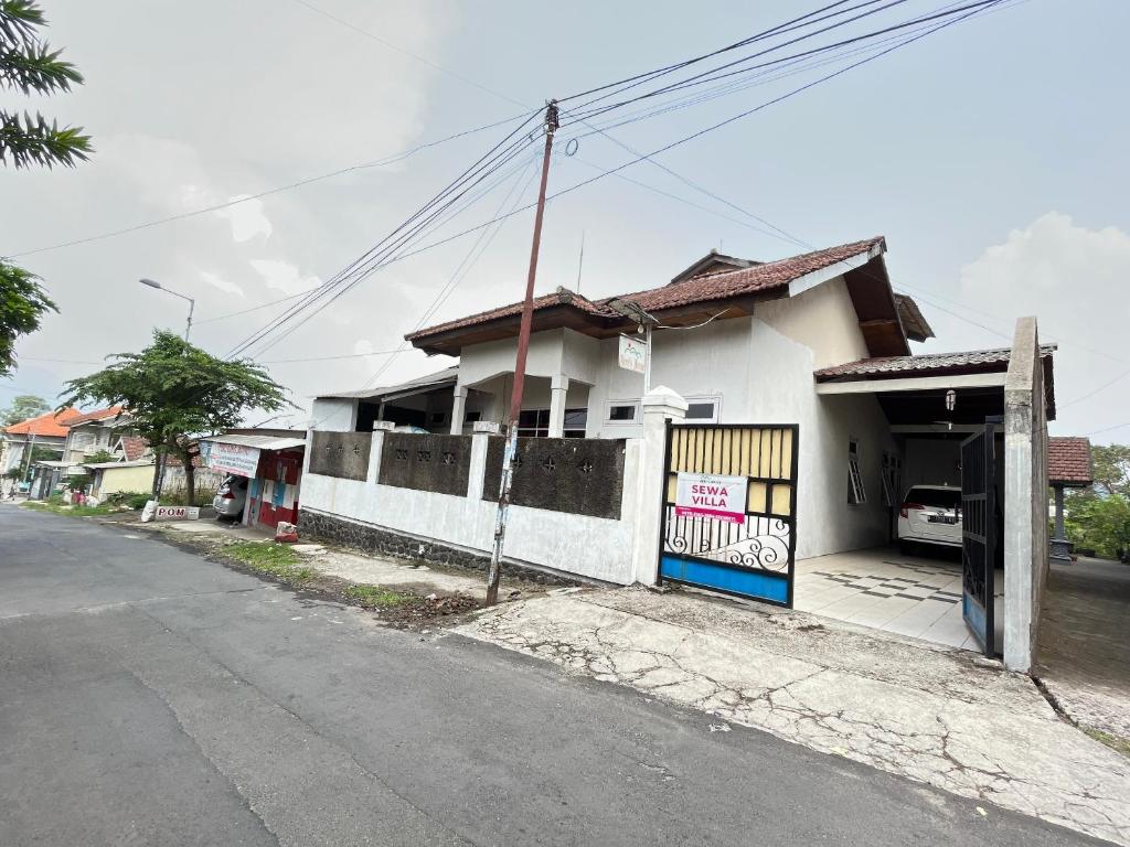 una casa blanca con una puerta en una calle en OYO 93629 Villa Cemara Syariah en Mojokerto