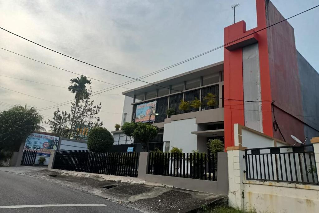 a building with a fence next to a street at OYO 93635 Rumah Singgah Cemara Syariah in Pekanbaru