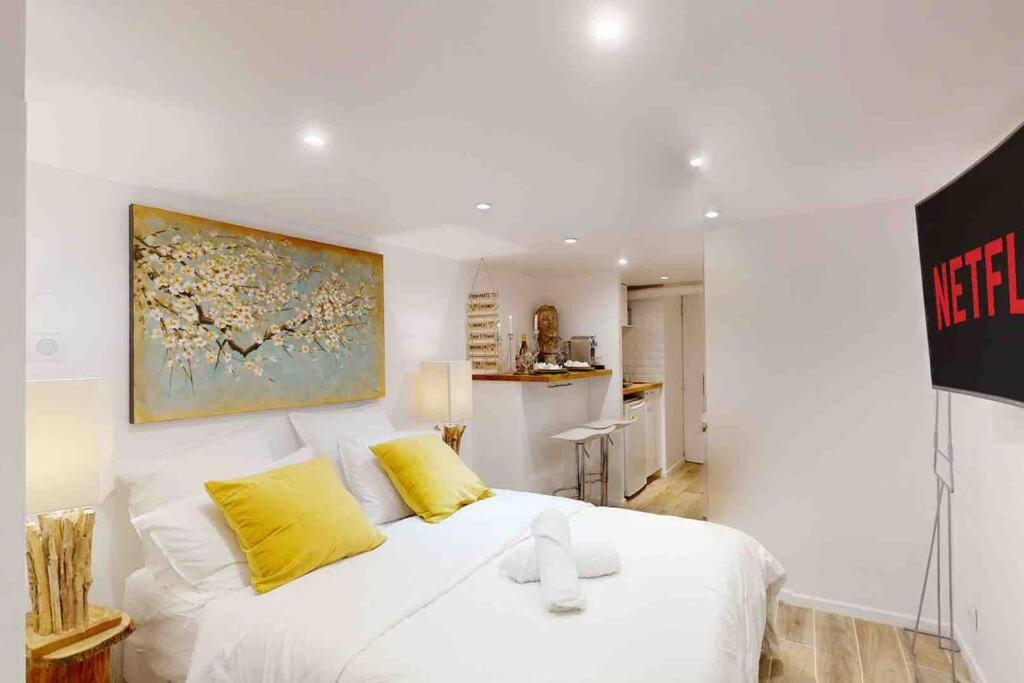 um quarto branco com uma cama branca e almofadas amarelas em Studio 1 Adorable studio neuf en bord de Marne 5kms Paris em Champigny-sur-Marne