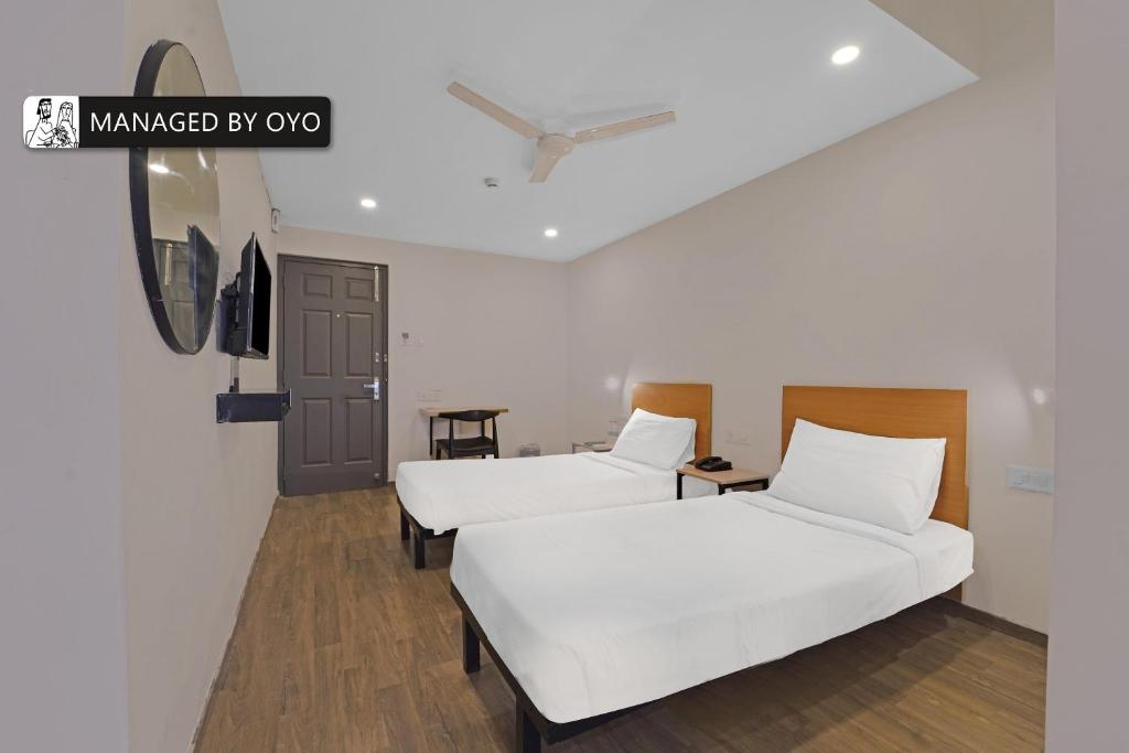 two beds in a room with white sheets at Super Townhouse OMR Laxmi Nagar in Chennai