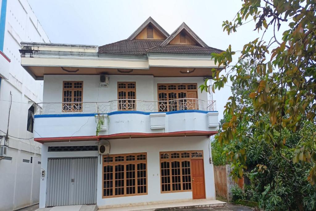 a white house with a balcony on top of it at OYO 93652 Karunia Kost & Penginapan 