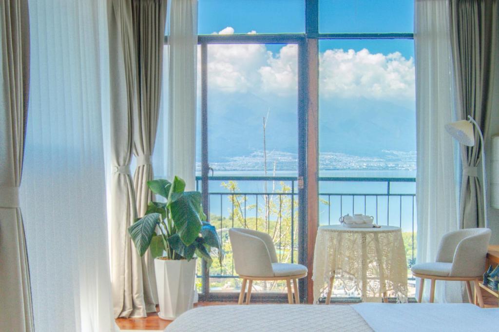 大理市にあるDali Erhai Forest River View Hostelのベッドルーム1室(海の景色を望む大きな窓付)