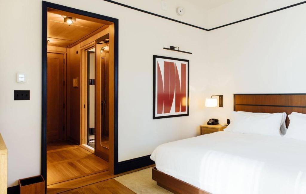 a bedroom with a large white bed and a hallway at Shinola Hotel in Detroit