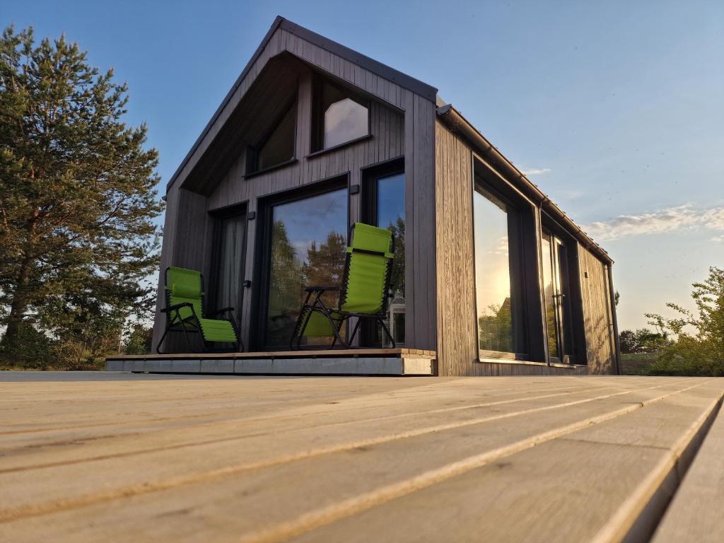 uma casa com cadeiras verdes num deque em The Sound of Silence - romantic tiny house near Riga em Salaspils