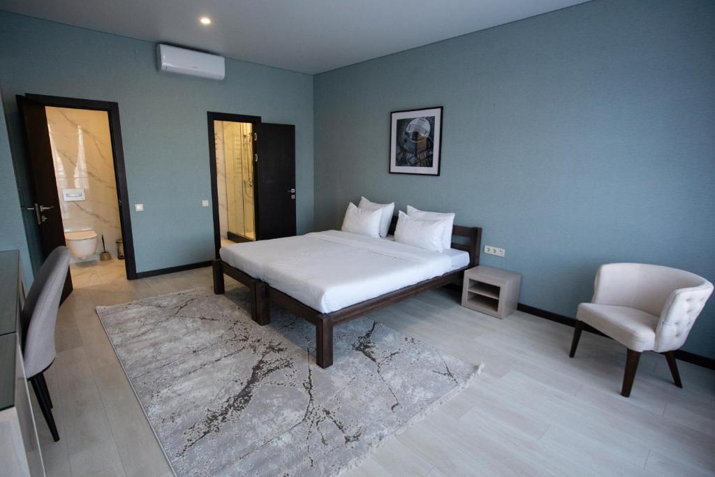 Arman Dala Resort في Qaskeleng: غرفة نوم بسرير ابيض وكرسي