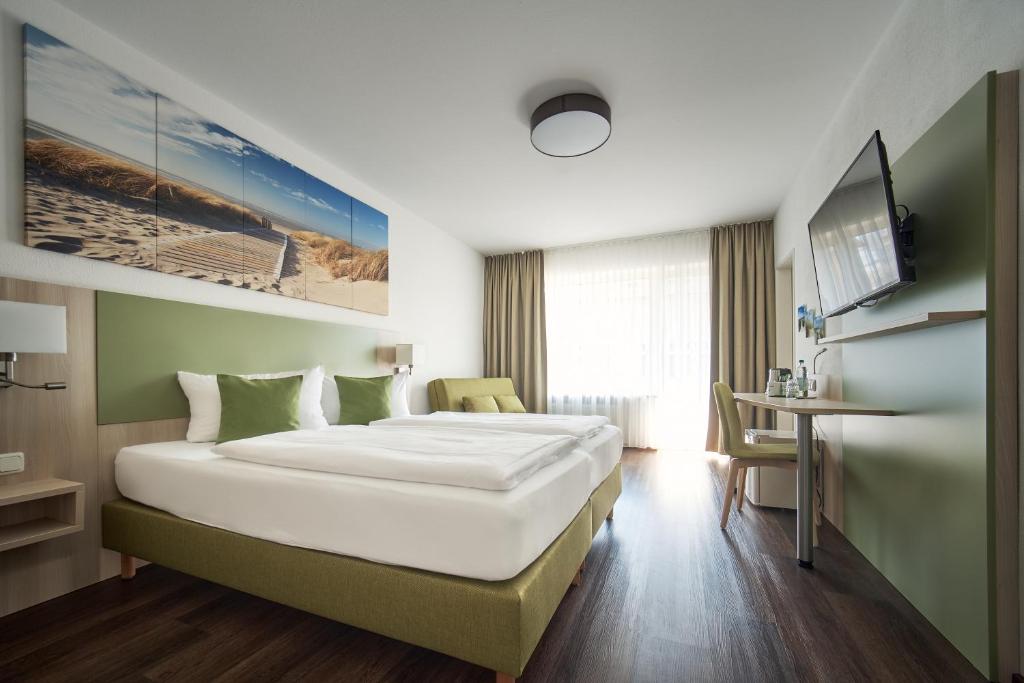 a hotel room with a large bed and a desk at Marias Inn Living - Hotel & Apartments Garching bei München in Garching bei München