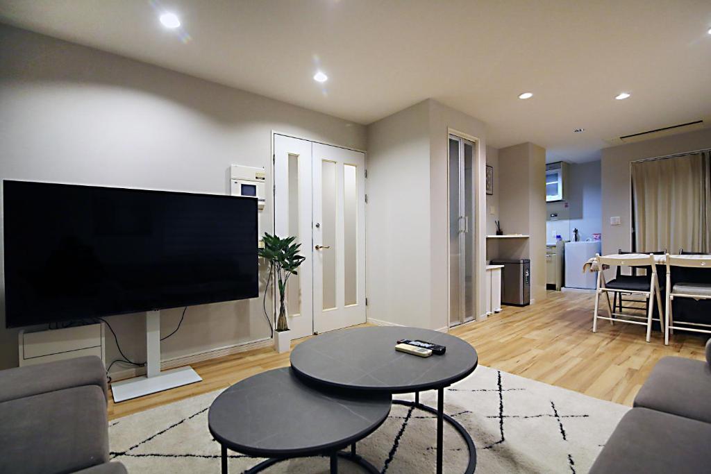 SUN House free Wifi في طوكيو: غرفة معيشة مع تلفزيون بشاشة مسطحة على جدار