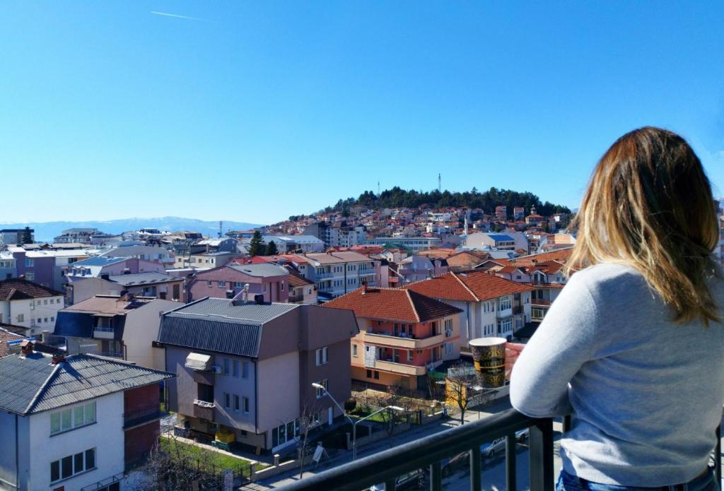 Eine Frau steht auf einem Balkon mit Blick auf eine Stadt in der Unterkunft Urban Vista Apartments in Ohrid