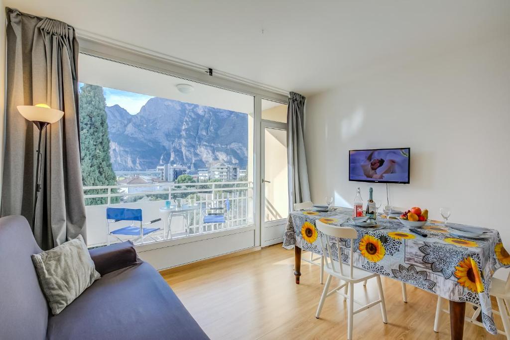 a living room with a table and a large window at Il Piccolo Nido - Happy Rentals in Riva del Garda