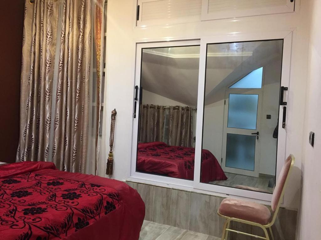 - une chambre avec une grande fenêtre et un lit rouge dans l'établissement La belle au bois dormant, à Abomey-Calavi