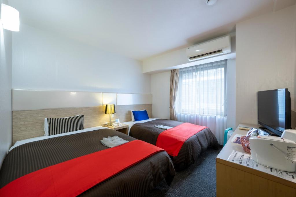 een hotelkamer met 2 bedden en een flatscreen-tv bij Hotel 1-2-3 Takasaki in Takasaki