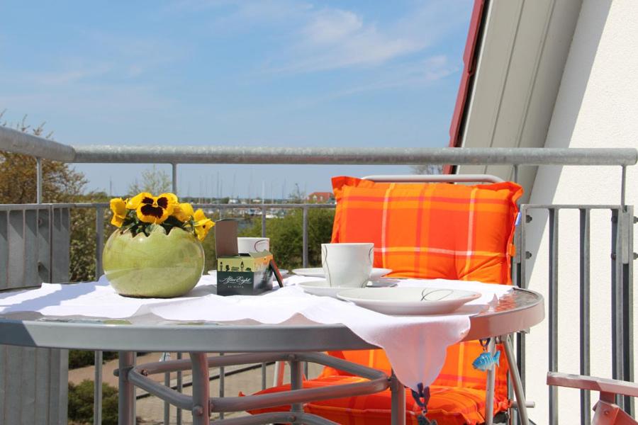 a table with a cup and a vase of flowers on a balcony at Ferienwohnung Luv - direkt am Salzhaff in Rerik
