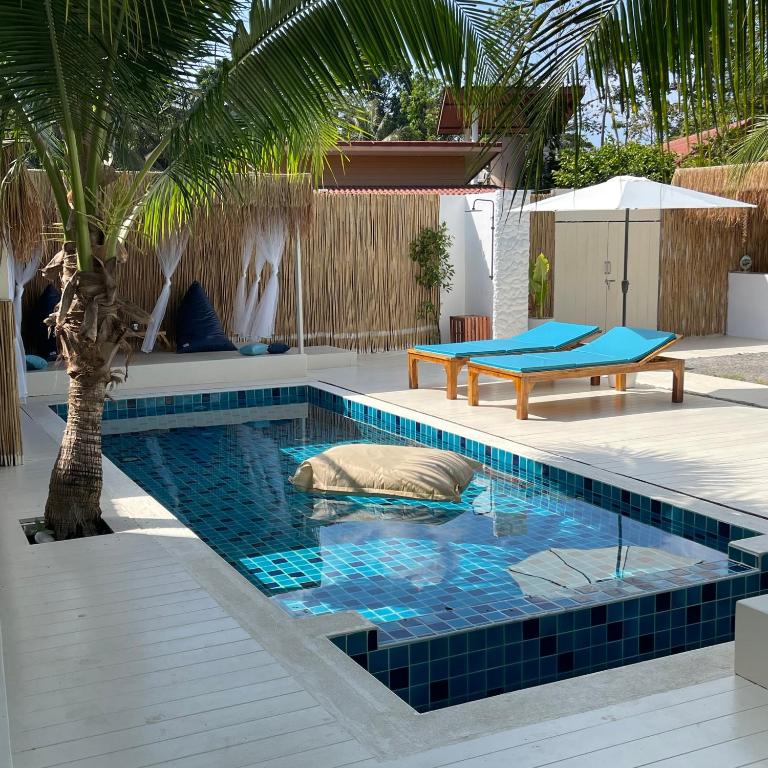 a swimming pool with a palm tree in a backyard at Acqualanta House in Ko Lanta