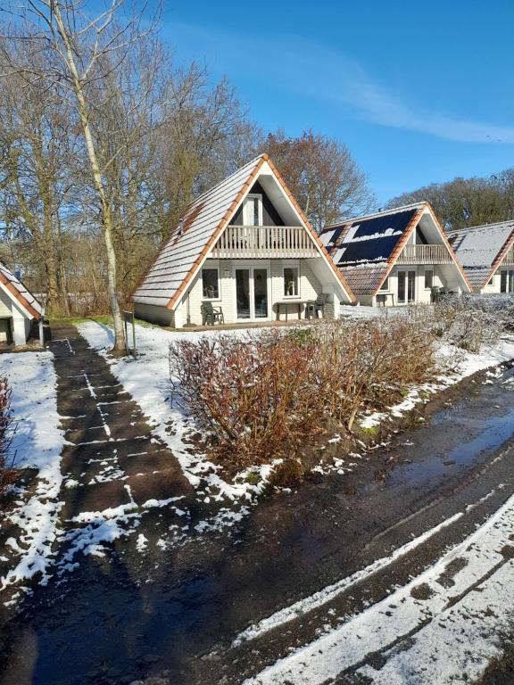 a house with snow on the ground next to a road at t'Hoog Holt in Gramsbergen