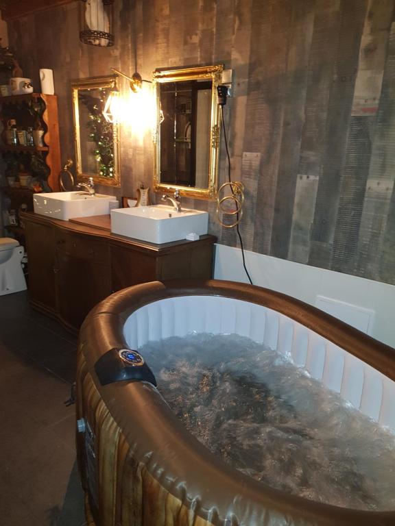 a bathroom with a tub with two sinks and a mirror at La Pensine du célèbre sorcier in Bourogne