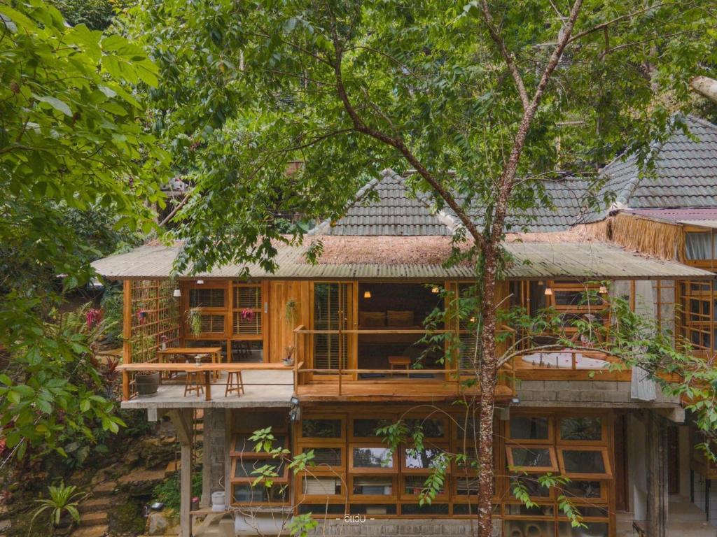 a house in the woods with a tree at Woo Ma Ca Moo in Chiang Mai