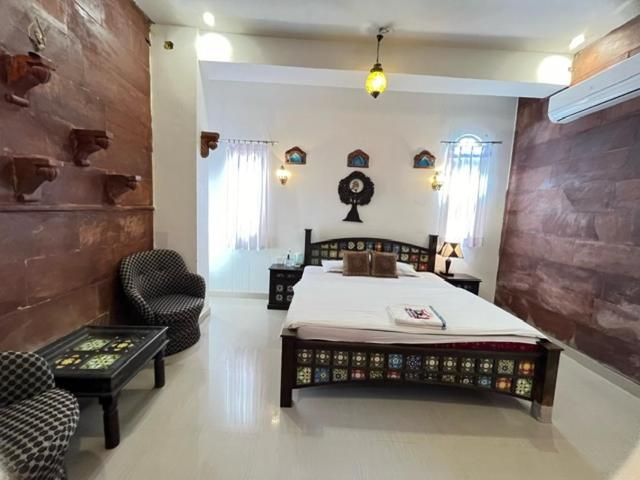 a bedroom with a large bed and a chair at Karma Homestay A Heritage Home in Jodhpur