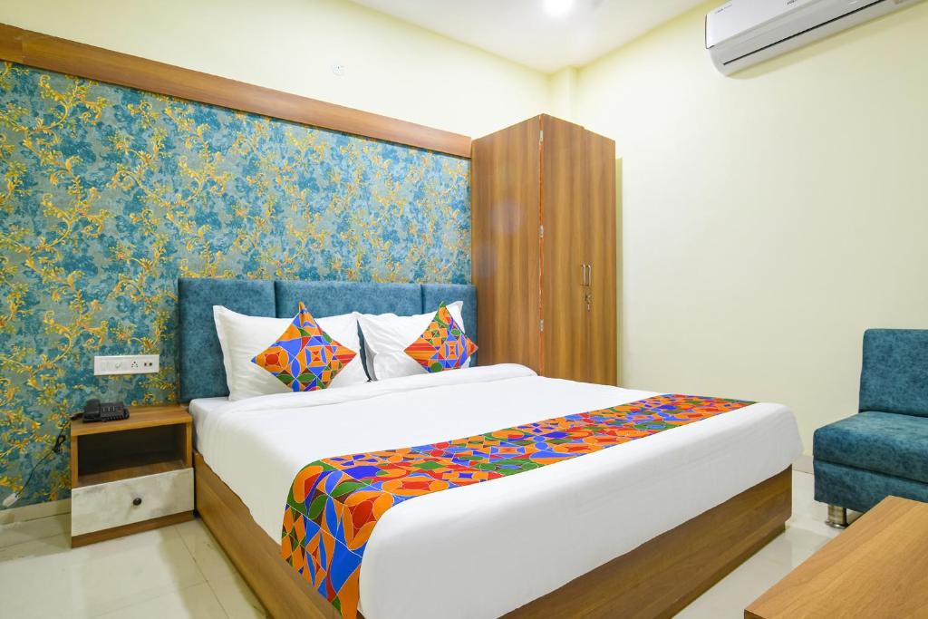 a bedroom with a bed and a blue chair at FabHotel Grand Giriraj in Indore