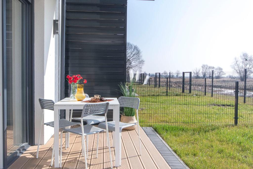 a table and chairs on a porch with a view of a field at Słoneczna Przystań-Apartamenty in Gdańsk