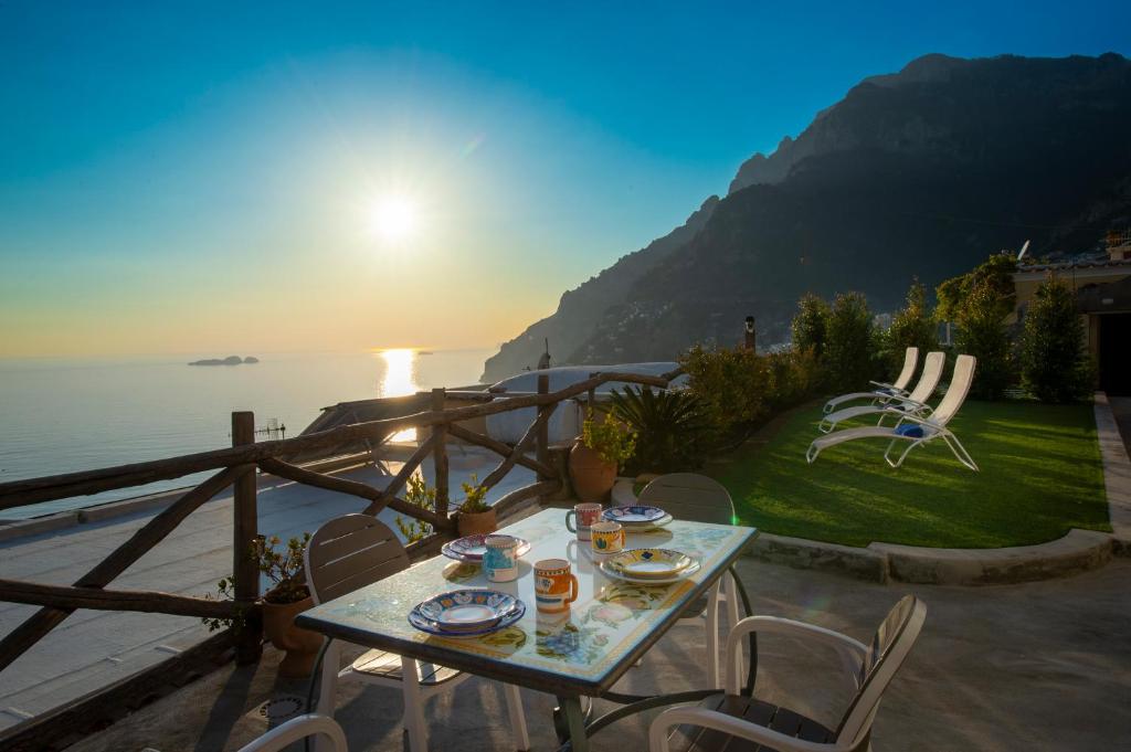 a table with plates of food on a balcony with the sunset at Aria di Mare, garden and Sea View in Positano in Positano