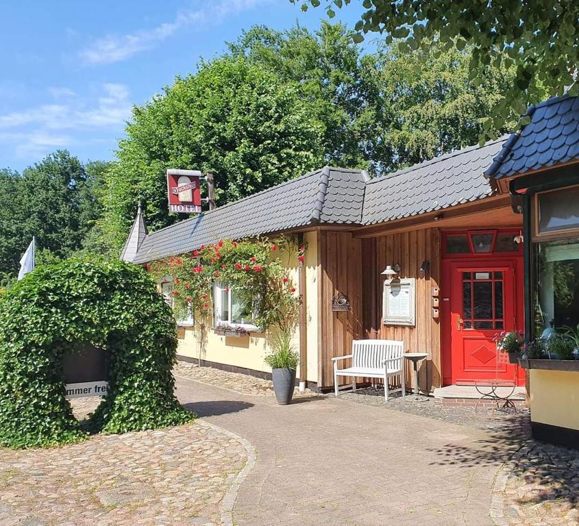 una pequeña casa con una puerta roja y un banco en Hotel Kropper Busch Garni en Kropp