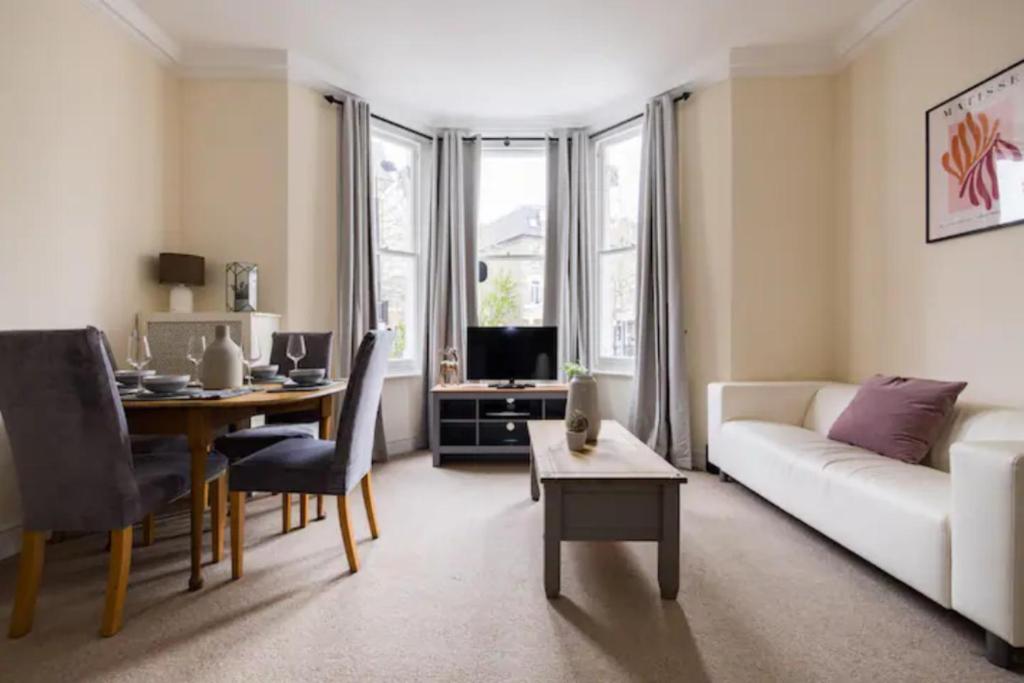een woonkamer met een witte bank en een tafel bij The West Kensington Collection in Londen