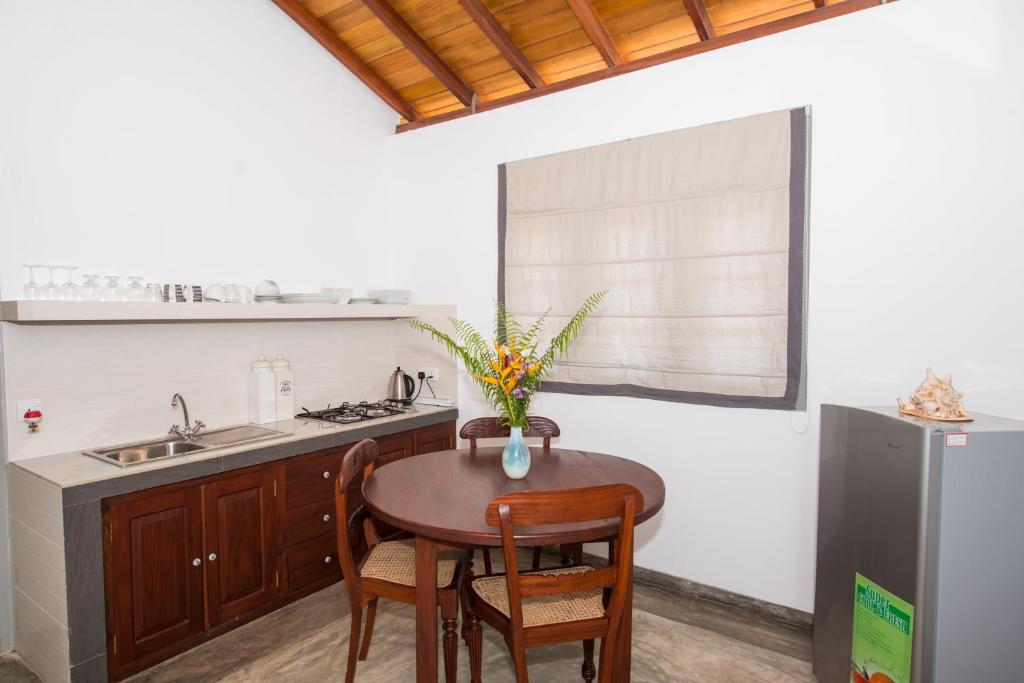 a kitchen with a table and a sink and a refrigerator at The Horizon Hill Top Villa in Unawatuna