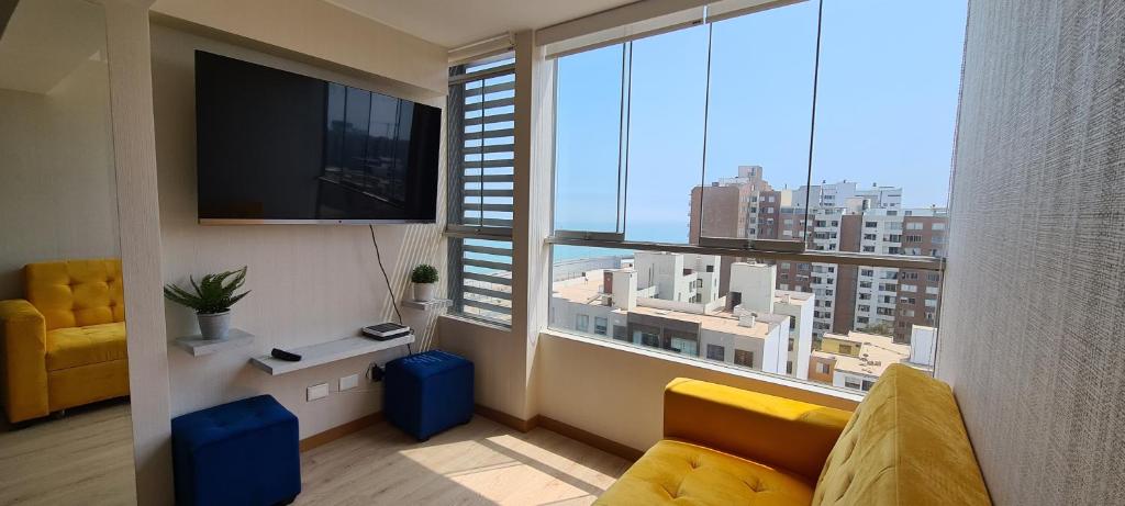 a living room with a large window with a view of a city at Acogedor departamento con vista al mar in Lima