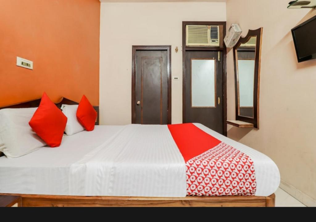 a bedroom with a bed with red and white pillows at Hotel sunrise in Lucknow