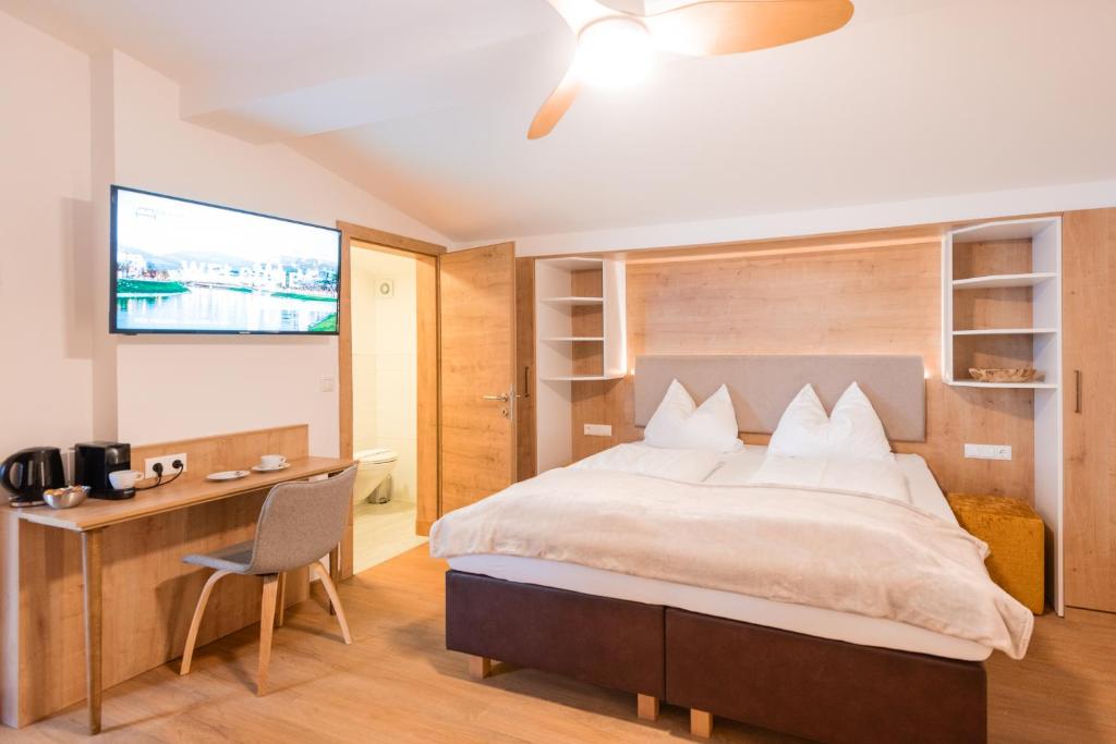 Schlafzimmer mit einem Bett, einem Schreibtisch und einem TV in der Unterkunft Hotel Modus in Salzburg