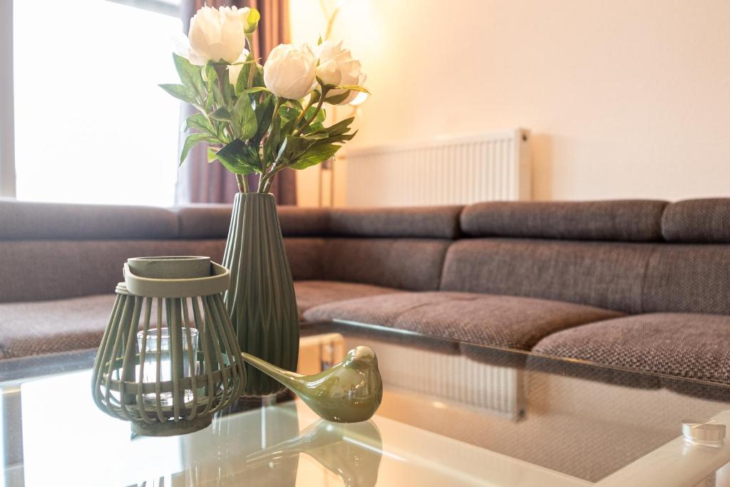 a vase with flowers on a glass table in a living room at Haus Ohragrund in Oberhof