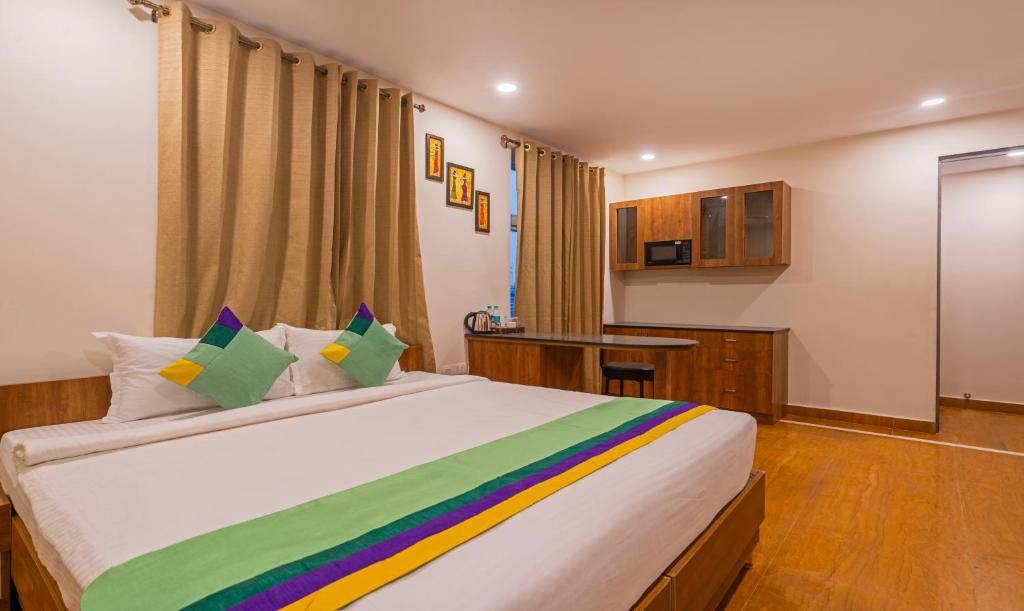 um quarto com uma grande cama branca com almofadas coloridas em Treebo Trend SY Inn - Gachibowli DLF em Hyderabad