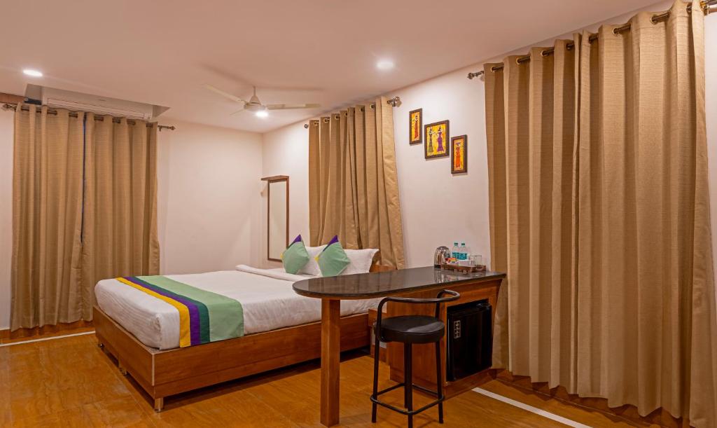 a bedroom with a bed and a desk and curtains at Treebo SY Inn, Gachibowli DLF in Hyderabad