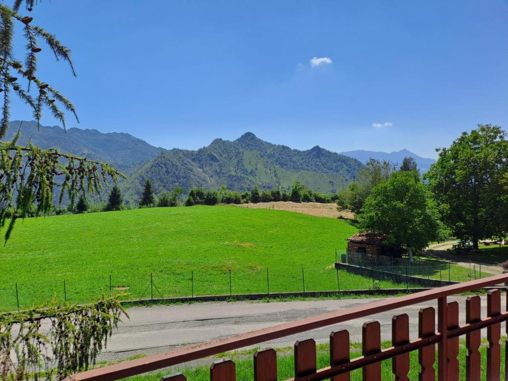 a field with a fence and mountains in the background at 181 - Casa Arcobaleno tra le Alpi, Piste da sci a 15 minuti in Castione della Presolana