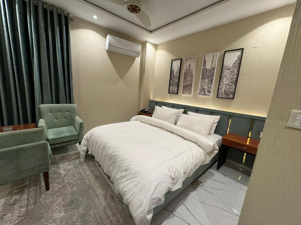 a hotel room with a bed and a chair at Shelton Boulevard Hotel Lahore in Lahore