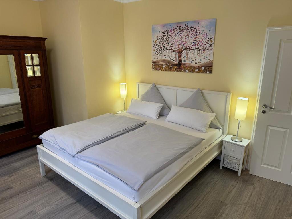a bedroom with a white bed with a painting on the wall at Pension Auszeit Ferienwohnung in Bad Neuenahr-Ahrweiler