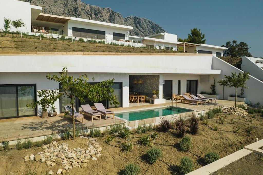 una villa con piscina di fronte a una casa di Private pool with prime location Oraio Meros a Paleros