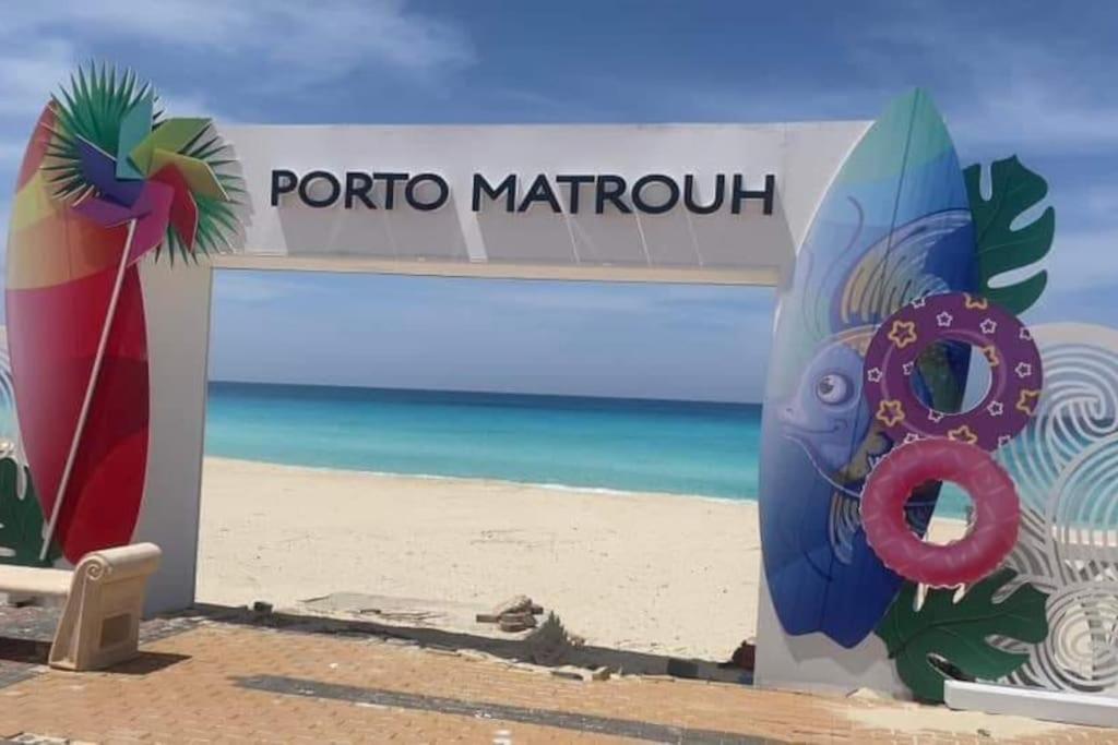 un cartel en una playa con un cartel para un popular puerto en Porto Matrouh unique Chalet en Marsa Matruh